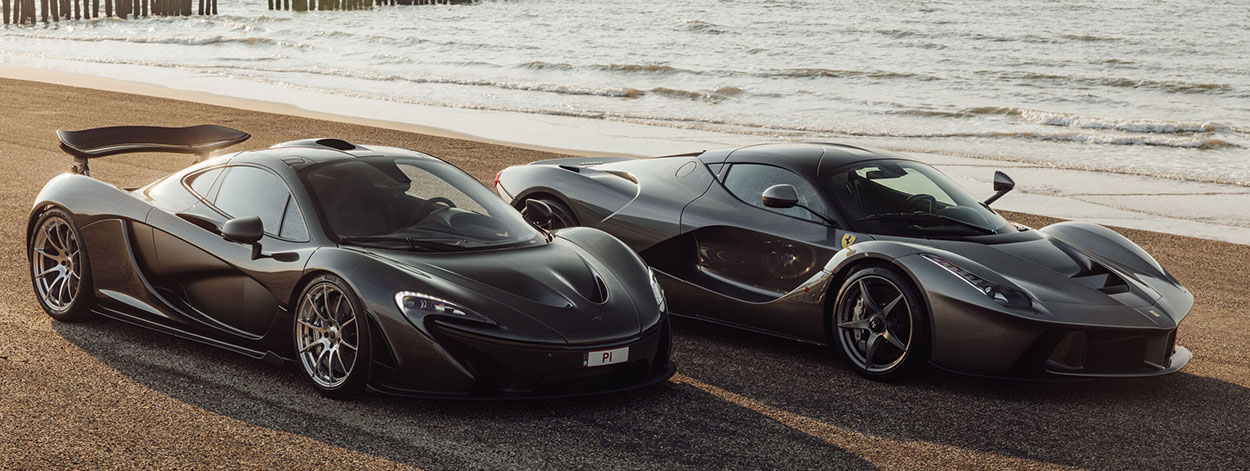 Hypercars McLaren P1 et Ferrari LaFerrari gris foncé garées sur la côte au coucher du soleil