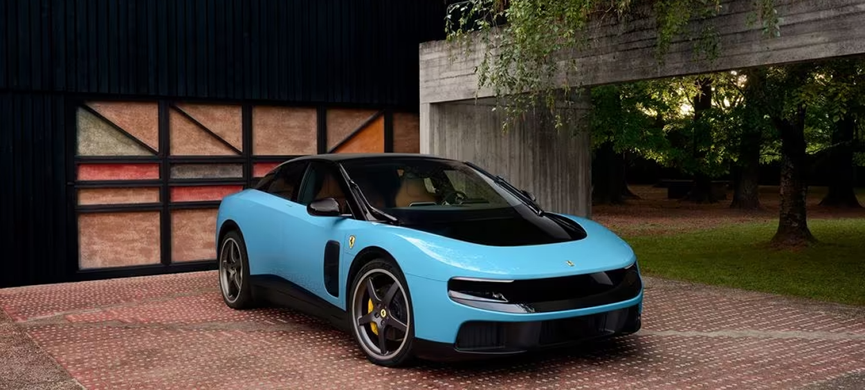 alt="Ferrari Luce électrique bleu clair de trois-quarts face garée devant une architecture moderne en béton et bois"