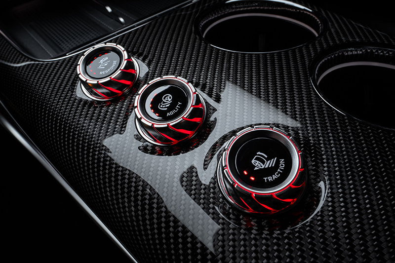 Gros plan sur la console centrale en fibre de carbone de la Mercedes-AMG GT électrique, montrant les trois molettes rotatives de l'AMG RACE ENGINEER : Response, Agility et Traction.