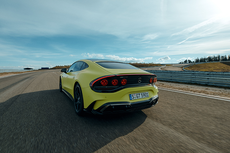 Vue arrière trois-quarts de la nouvelle Mercedes-AMG GT Coupé 4 portes électrique jaune sur circuit, mettant en valeur ses feux ronds signatures et son diffuseur actif AEROKINETICS.
