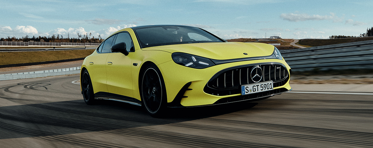 Nouvelle Mercedes-AMG GT Coupé 4 portes électrique jaune en pleine accélération sur un circuit de course lors d'essais dynamiques.