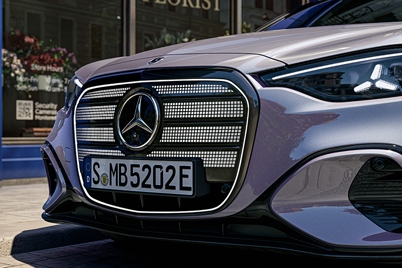 Gros plan sur la calandre illuminée de la Mercedes Classe C électrique arborant un motif de 1 050 étoiles lumineuses et le logo central Mercedes-Benz.