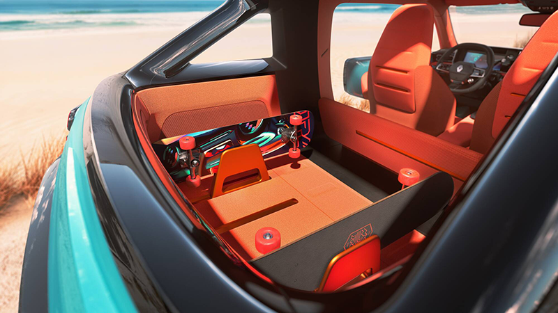 Zoom sur le coffre ouvert de la Renault 4 JP4x4 Concept avec ses skateboards intégrés et son aménagement intérieur orange face à la plage.