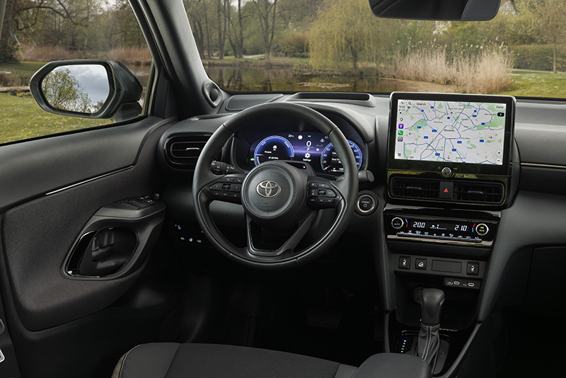 Vue de l'habitacle de la Toyota Yaris Cross 2026 avec les nouveaux inserts couleur platine, les sièges sport en matériau recyclé SakuraTouch et l'écran central Toyota Smart Connect.  Légende Photo (Style éditorial)