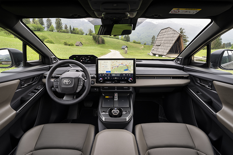 Habitacle du Toyota bZ4X Touring 2026 AWD Bronze, cockpit numérique horizontal, grand écran multimédia 14 pouces, console centrale avec sélecteur rotatif et nouvelle sellerie marron exclusive.
