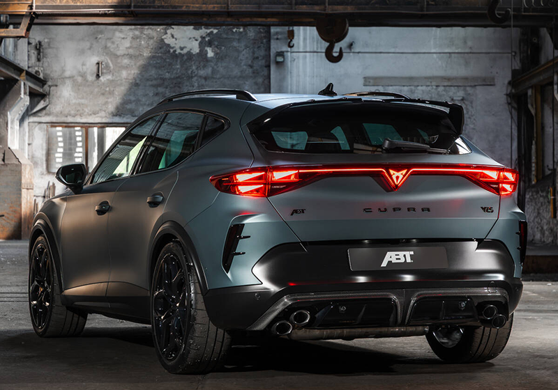 Vue de trois-quarts arrière du CUPRA Formentor VZ5 ABT de 635 ch en gris mat, mettant en avant l'aileron arrière noir brillant, les quatre sorties d'échappement sport et le diffuseur en carbone dans un décor d'usine désaffectée.
